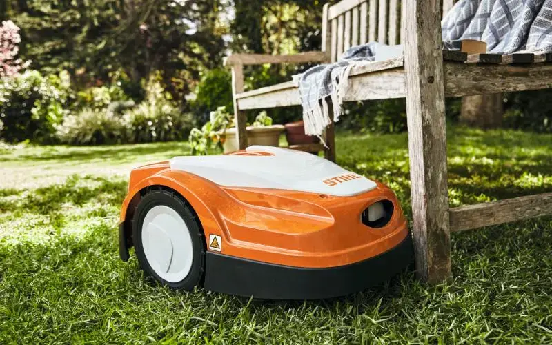 Ρομποτικό χλοοκοπτικό STIHL κόβει το γκαζόν δίπλα σε ξύλινο παγκάκι – Κατηγορία Περιποίηση Γκαζόν